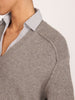 Close-up of the pullover v-neck sweater in otter melange with flint stripe, showing the ribbed knit collar over a striped shirt.