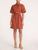 Woman wearing the Villa dress in Tuscany, a short-sleeve shirt dress with a waist tie, paired with beige strappy heels.