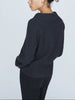 Back view of charcoal ribbed cashmere sweater with cowl neckline, worn with black pants.
