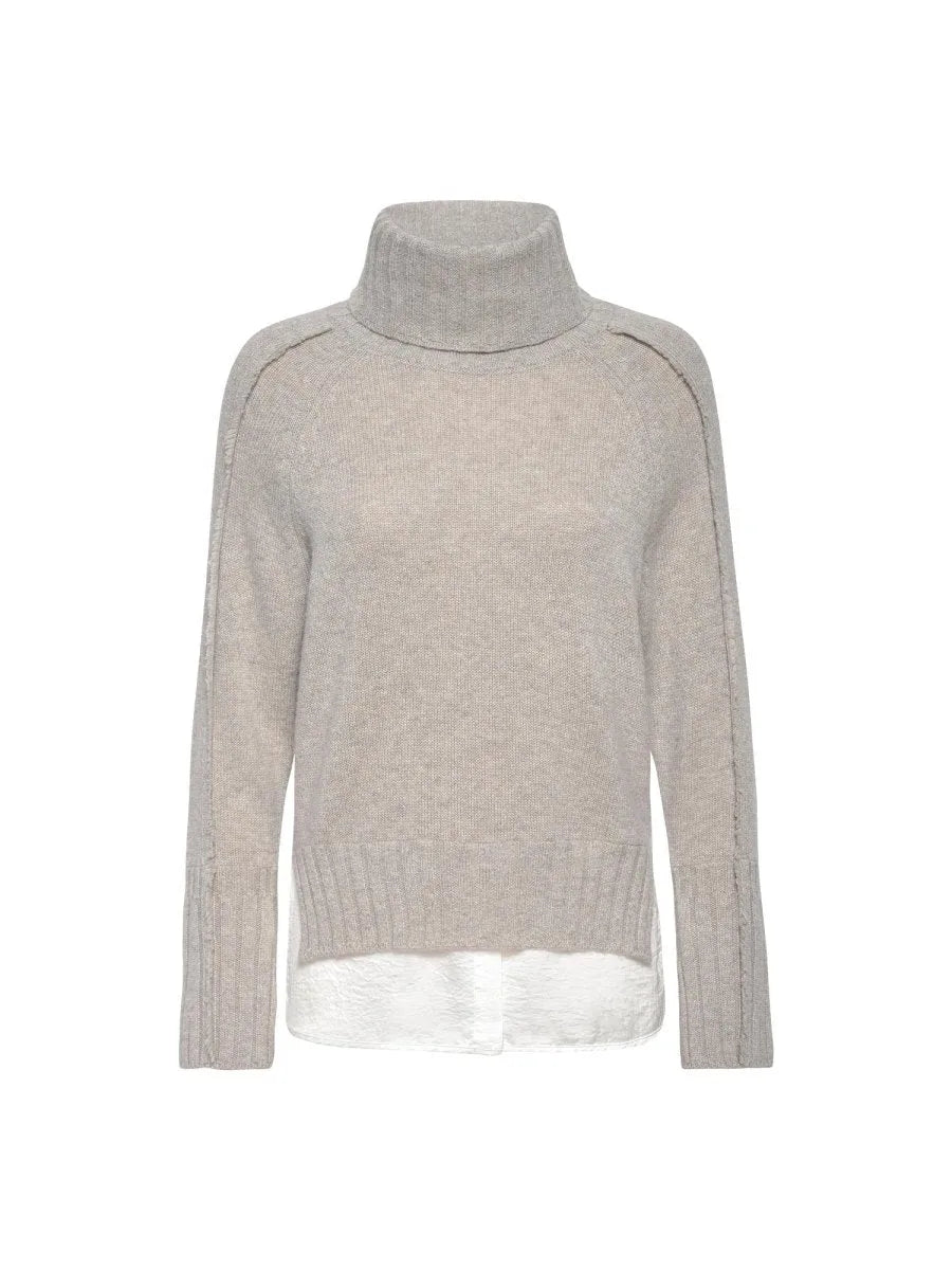 Beige layered sweater with turtleneck, raglan sleeves, and white satin underlayer visible at the hem.