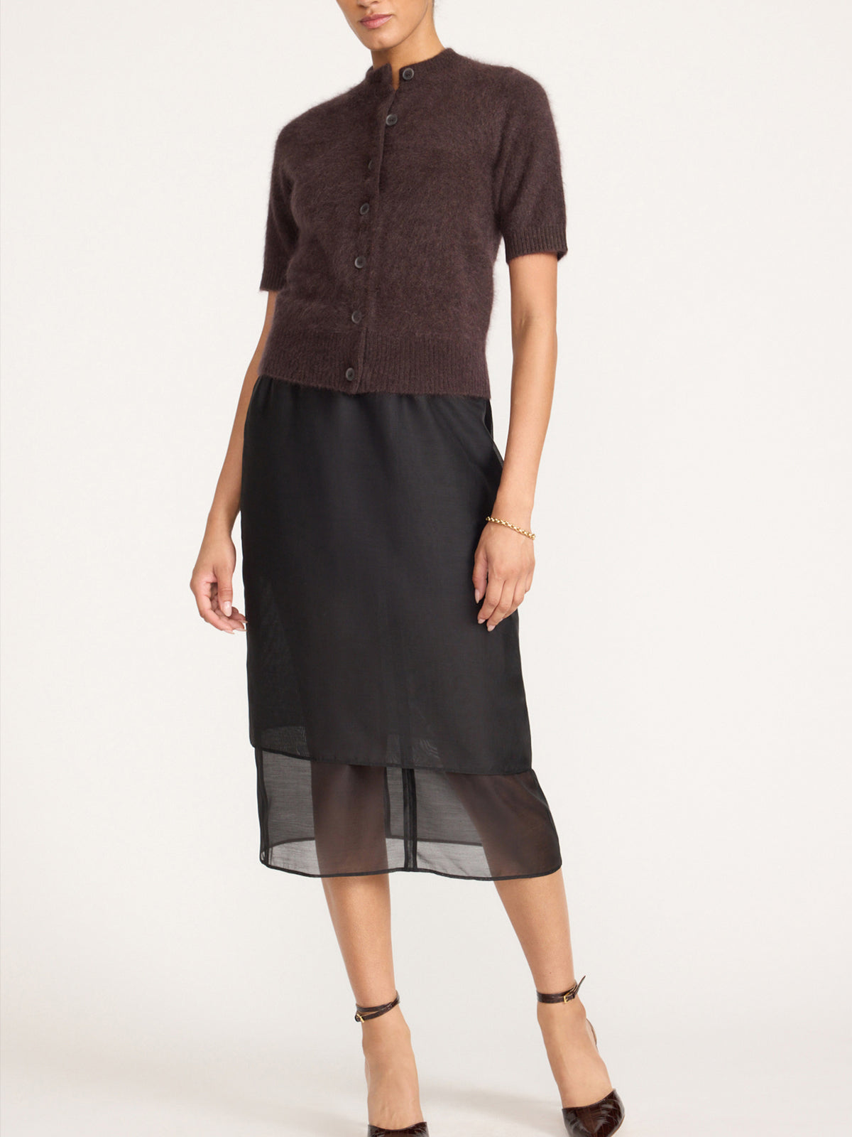 Women's short sleeve cashmere cardigan in dark brown with a button front, styled with a black skirt with a sheer hem and black heels