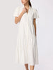 Close-up of a classy white tiered midi shirtdress with voluminous puff sleeves and a v-neckline button placket on a model.