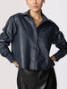 Cropped vegan leather shirt jacket in navy, styled with a black leather skirt, hands in pockets