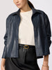 Cropped vegan leather shirt jacket in navy, layered over a cream top with a black leather skirt and gold belt