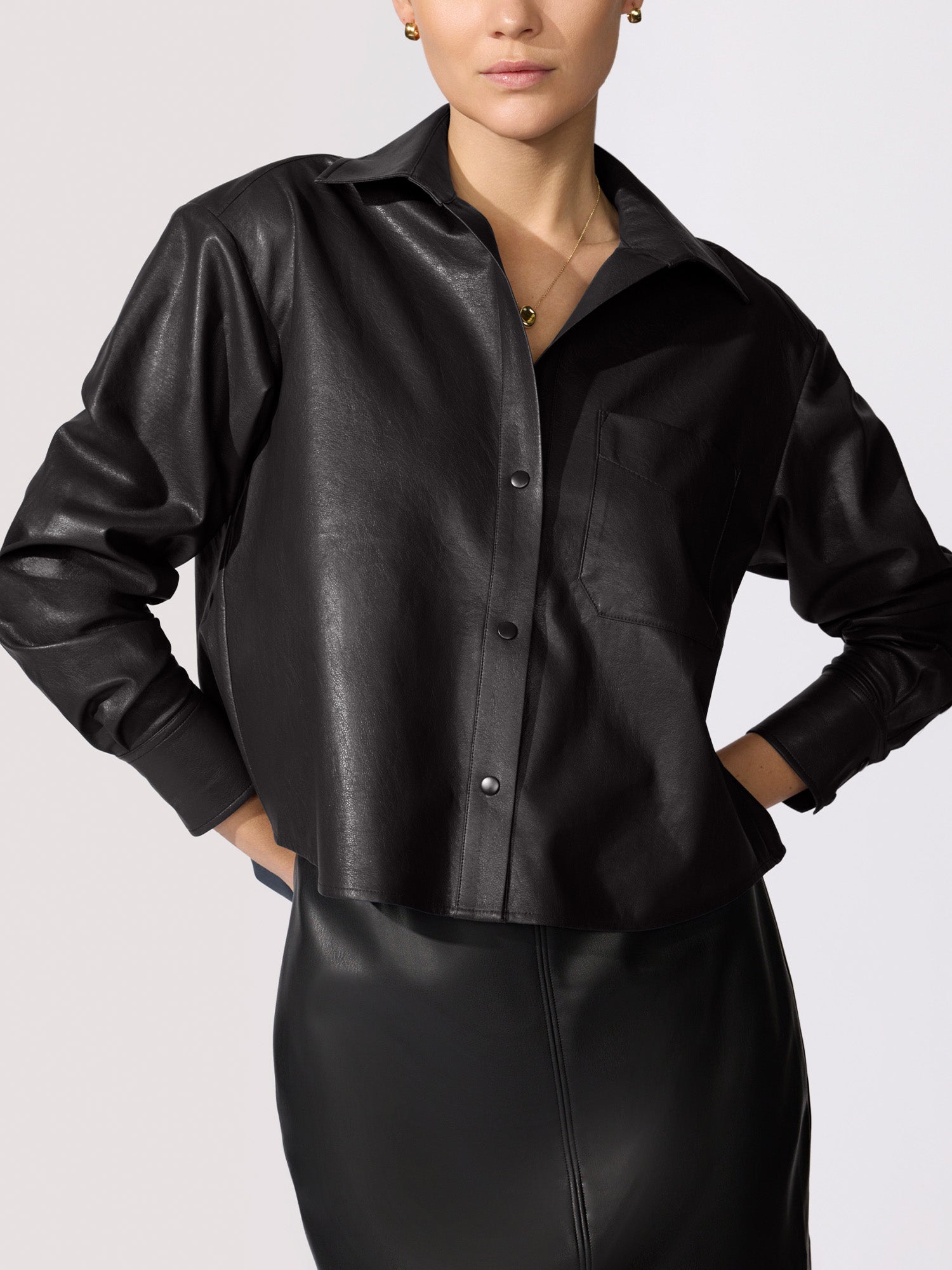 Cropped vegan leather shirt jacket in black, close-up with matching black leather skirt