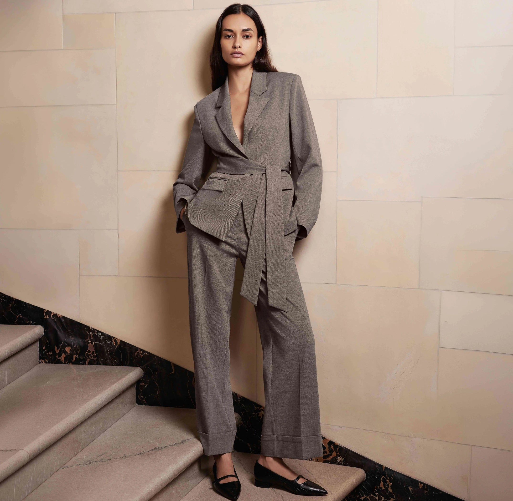 Woman wearing a gray women's suiting set with tie-front blazer and wide-leg trousers