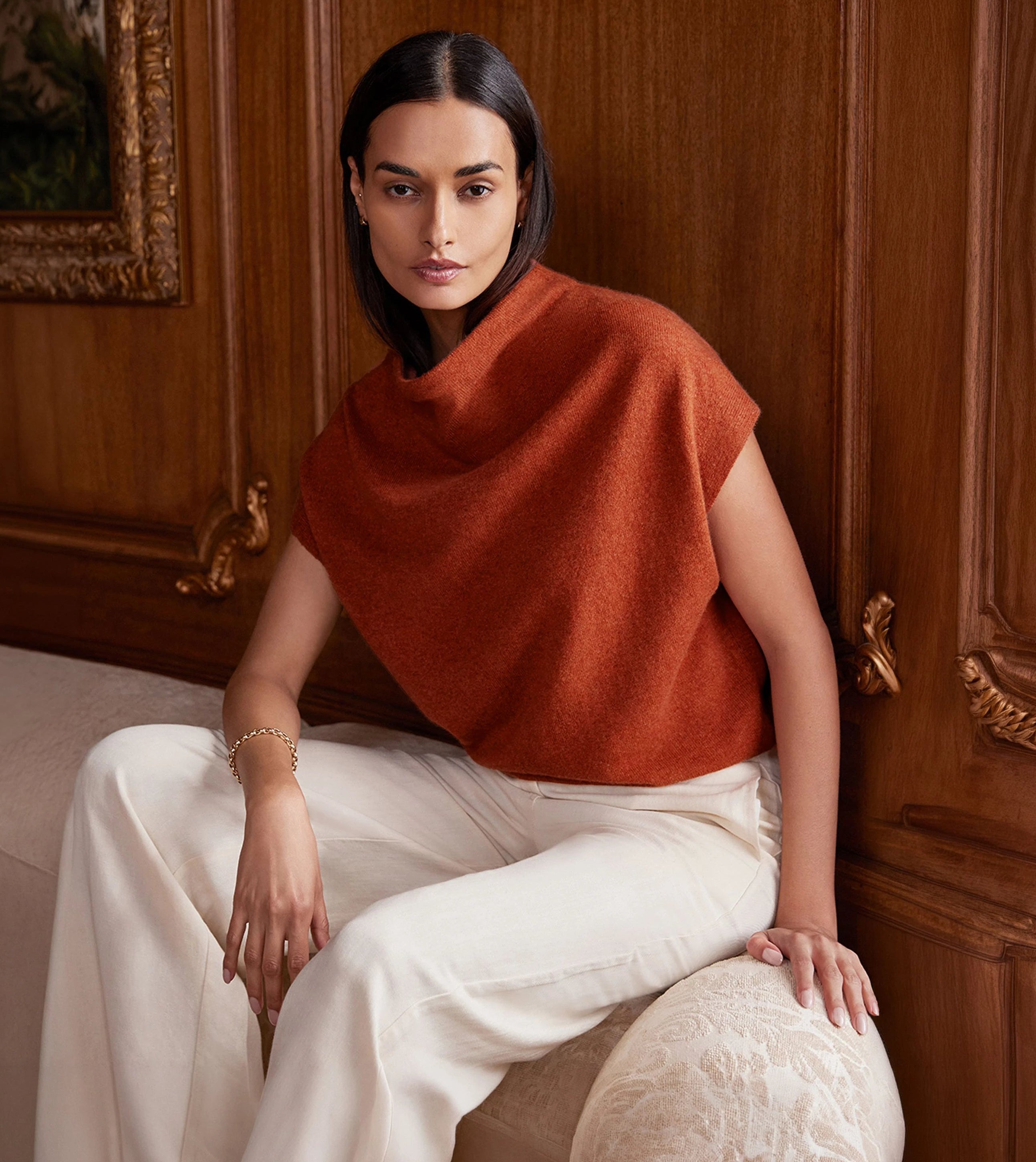 Woman wearing a rust lightweight women's cashmere top with white wide-leg trousers