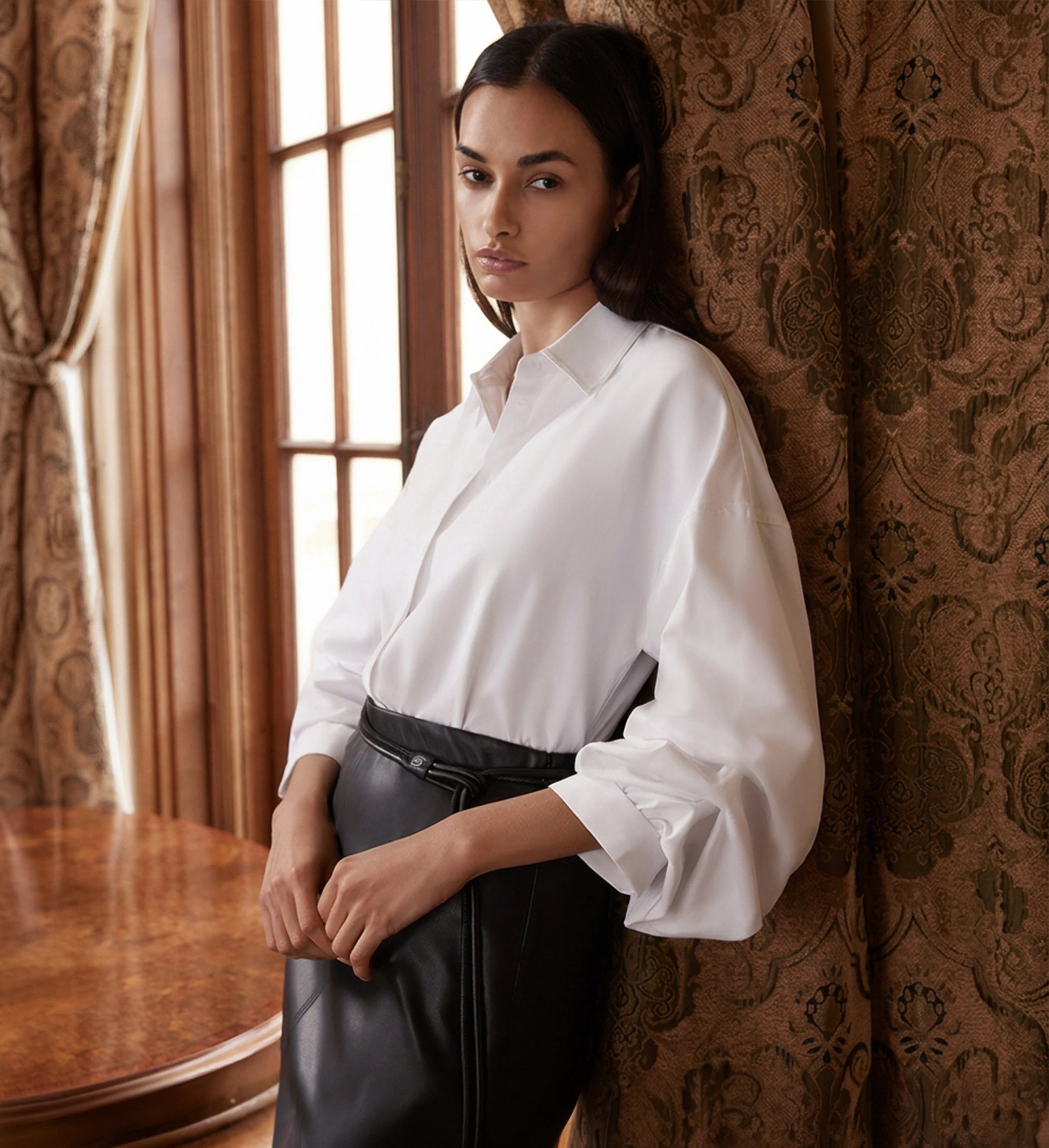 Woman wearing a white women's blouse with billowy sleeves and black leather trousers