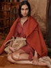 Wrap coat in rust orange, worn over a matching shirtdress, seated with a beige suede bucket bag