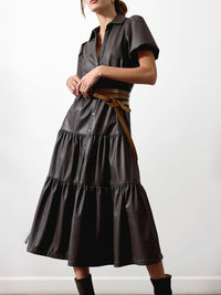 Brown vegan leather midi dress with tiered skirt, puff sleeves, and a tan wrap belt at the waist.