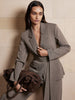 Belted blazer and trouser suit in taupe gray, styled with a brown suede handbag