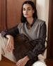 Woman wearing a gray women's sweater vest over a plaid shirt with a suede handbag