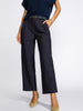Close-up of a model wearing navy pinstripe cropped trousers with a matching belt and beige heels, shown from the waist down against a light gray background.