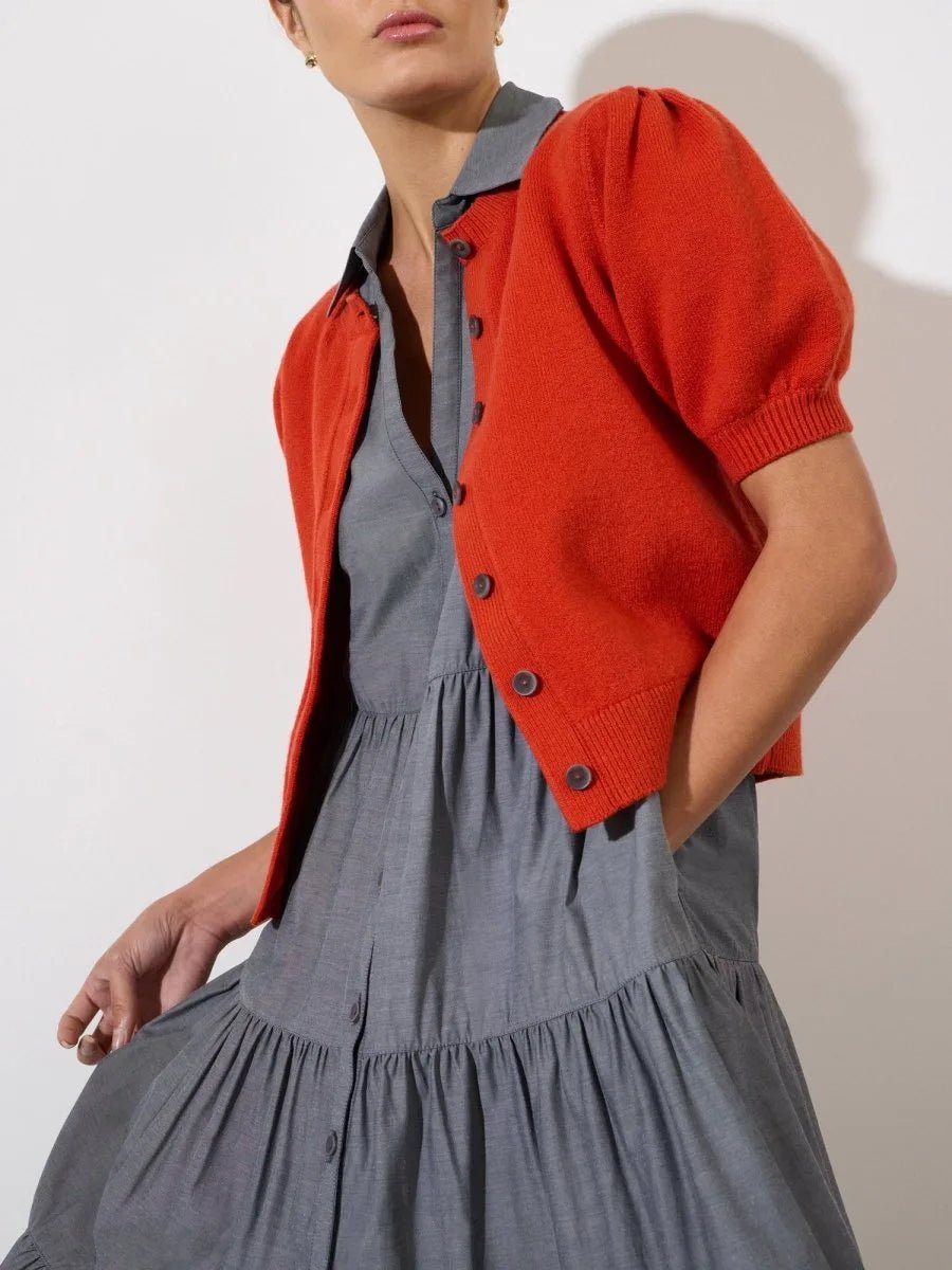 Slate gray tiered shirt dress with button front and v-neck, layered under an orange short-sleeve cardigan.