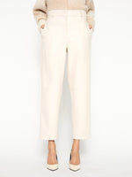 Ivory vegan leather pants with high waist, tapered legs, and front pockets, paired with a cream knit sweater and white heels.